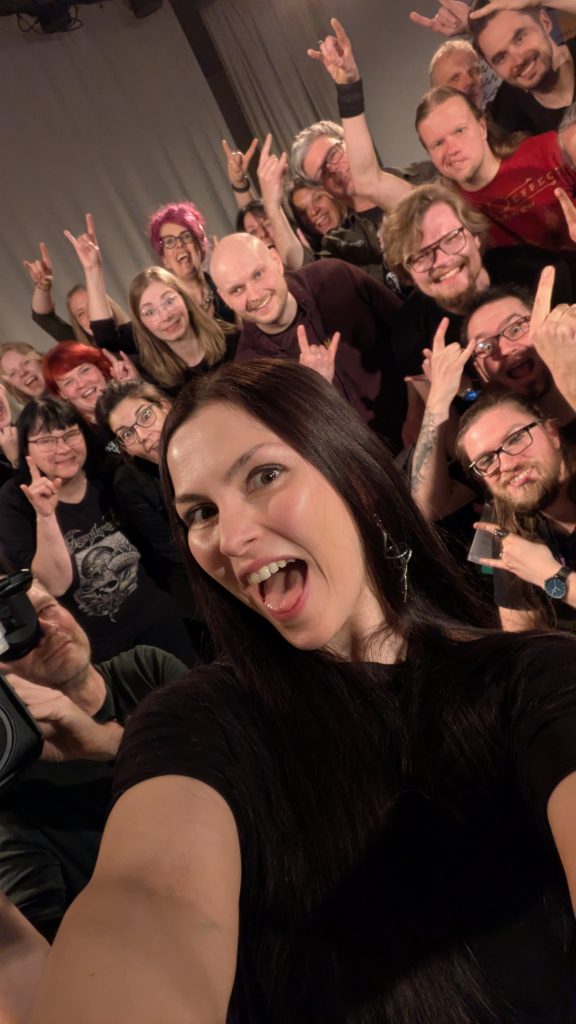 Eine Gruppe Menschen steht eng zusammen und lächelt fröhlich in die Kamera.