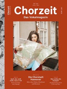 Chorzeit Nr. 114 (April 2024) Eine Person hält eine große Landkarte in den Händen und steht in einer Altstadtgasse. Die Themen sind Chorstadt Hannover, Repertoire-Tipps und Bergmannschöre.
