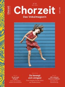Chorzeit Nr. 65 (November 2019) Cover mit rotem Hintergrund: Ein Mädchen in einem roten Kleid springt vor einer blauen, gestreiften Wand. Die Themen sind Entwicklung reifer Stimmen, Kinderchöre und die Bedeutung von Storytelling.