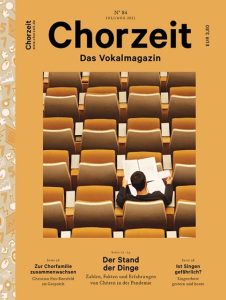 Chorzeit Nr. 84 (Juli/August 2021) Eine Person sitzt allein in einer großen, leeren Aula und liest in einem Heft. Die Themen sind Chorfamilie, Pandemie-Erfahrungen und Singen als Risiko.