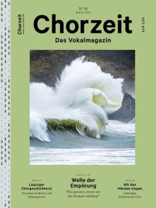 Chorzeit Nr. 91 (März 2022) Eine große grüne Welle bricht an der Küste, im Hintergrund Felsen und bewaldete Hügel. Die Ausgabe behandelt Empörung, Tradition und Inklusion im Chor.