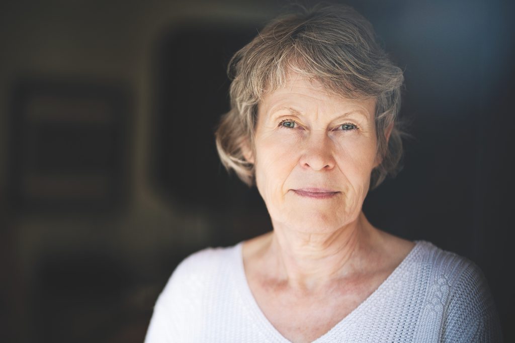 Eine weiß gelesene Frau mit eher kurzen, leicht ergrauten Haaren blickt aufmerksam in die Kamera.