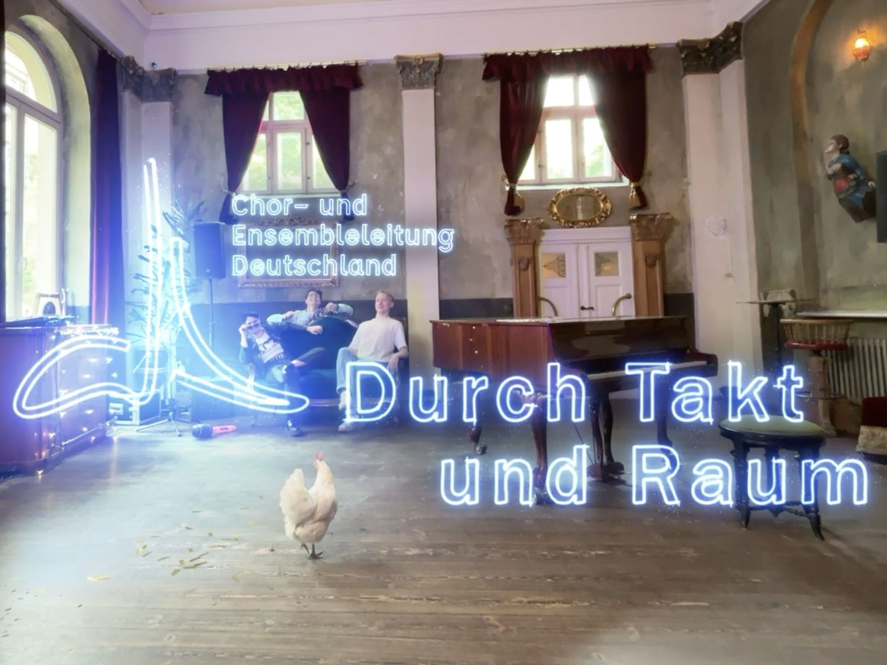 Drei Menschen sitzen auf einem Sofa und blicken erstaunt auf ein Huhn, das durch den Raum geht. Die Stimmung ist kreativ. In heller Schrift steht auf dem Bild: Durch Takt und Raum