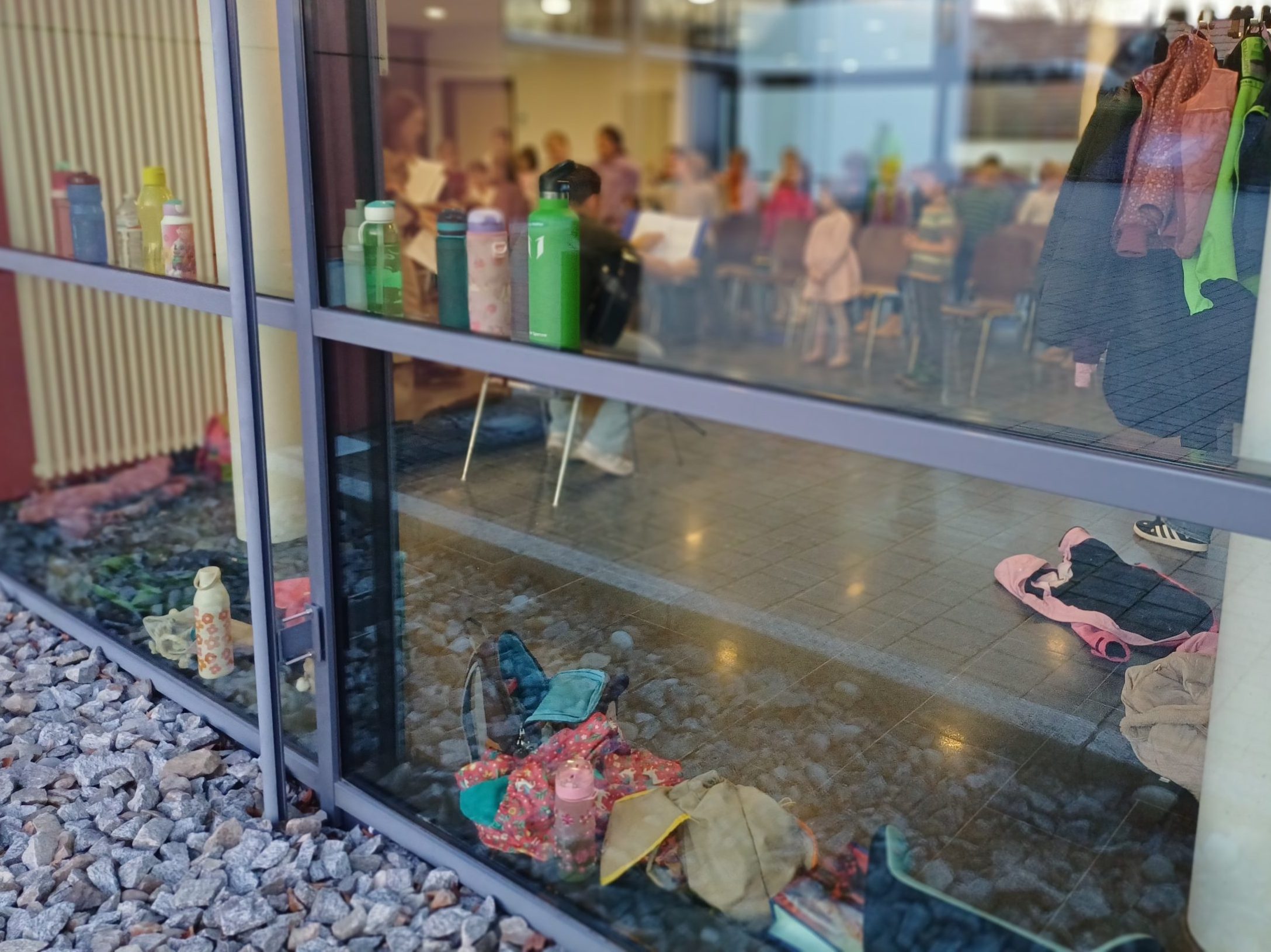 Ein Blick durch eine Fensterscheibe. Drinnen proben Kinder