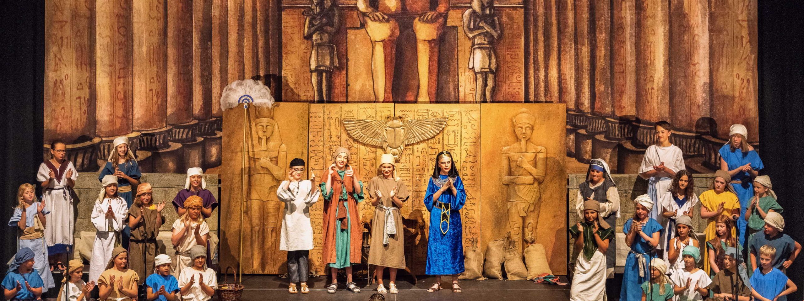 Ein großer Kinderchor steht auf monumentalen Kulissen mit Motiven des altertümlichen Agypten.
