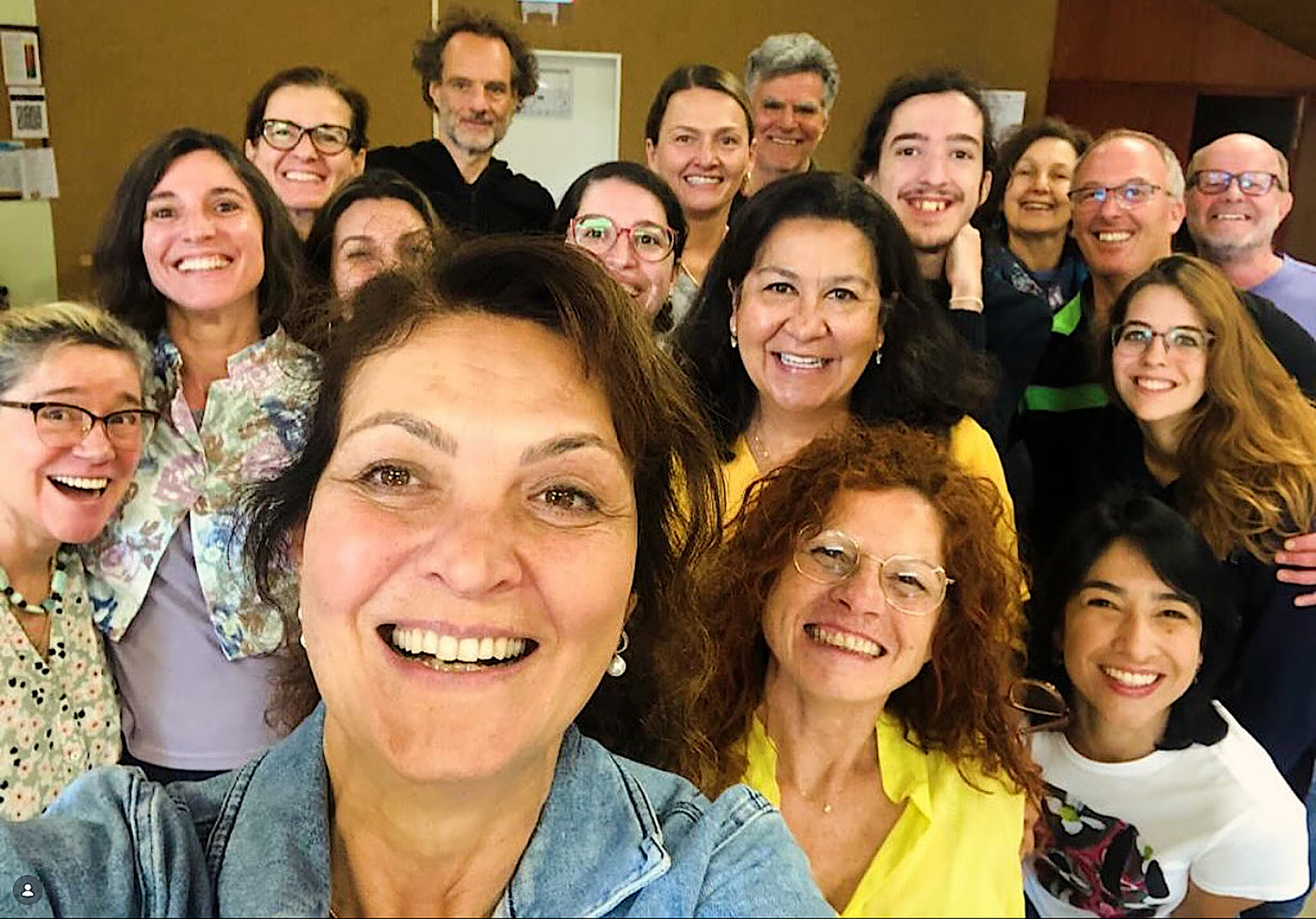 Ein Selfie einer Gruppe aus 16 fröhlich schauenden Männern und Frauen.