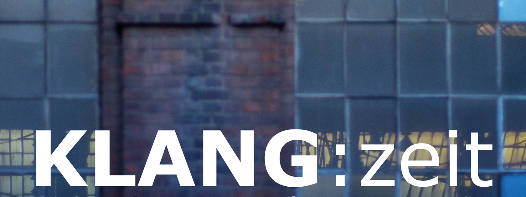 Ein altes Industriegebäude ist abgebildet mit Backsteinwänden und milchigen Fenstern. Darunter steht in weißer Schrift Klangzeit