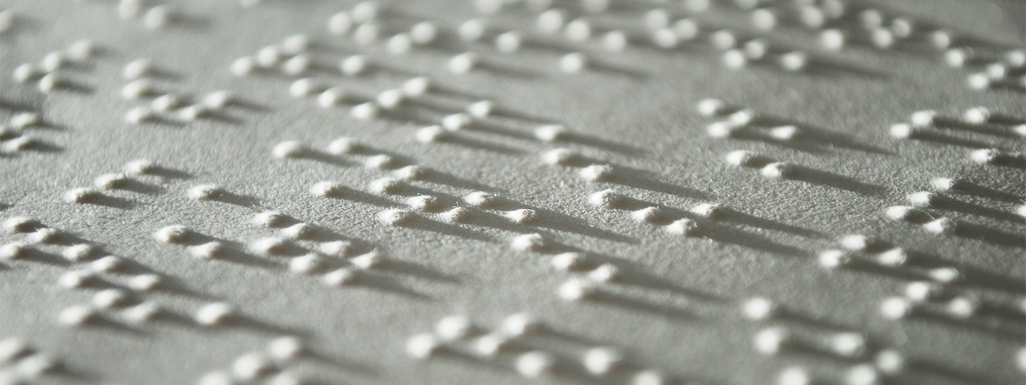 Auf Papier sind die typischen ausgestanzten Punkte der Brailleschrift zu erkennen.
